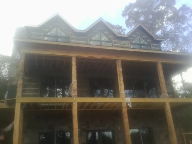 Dormers and porch framing on a large log home under construction — Roof Coating work by our crew in Stapleton