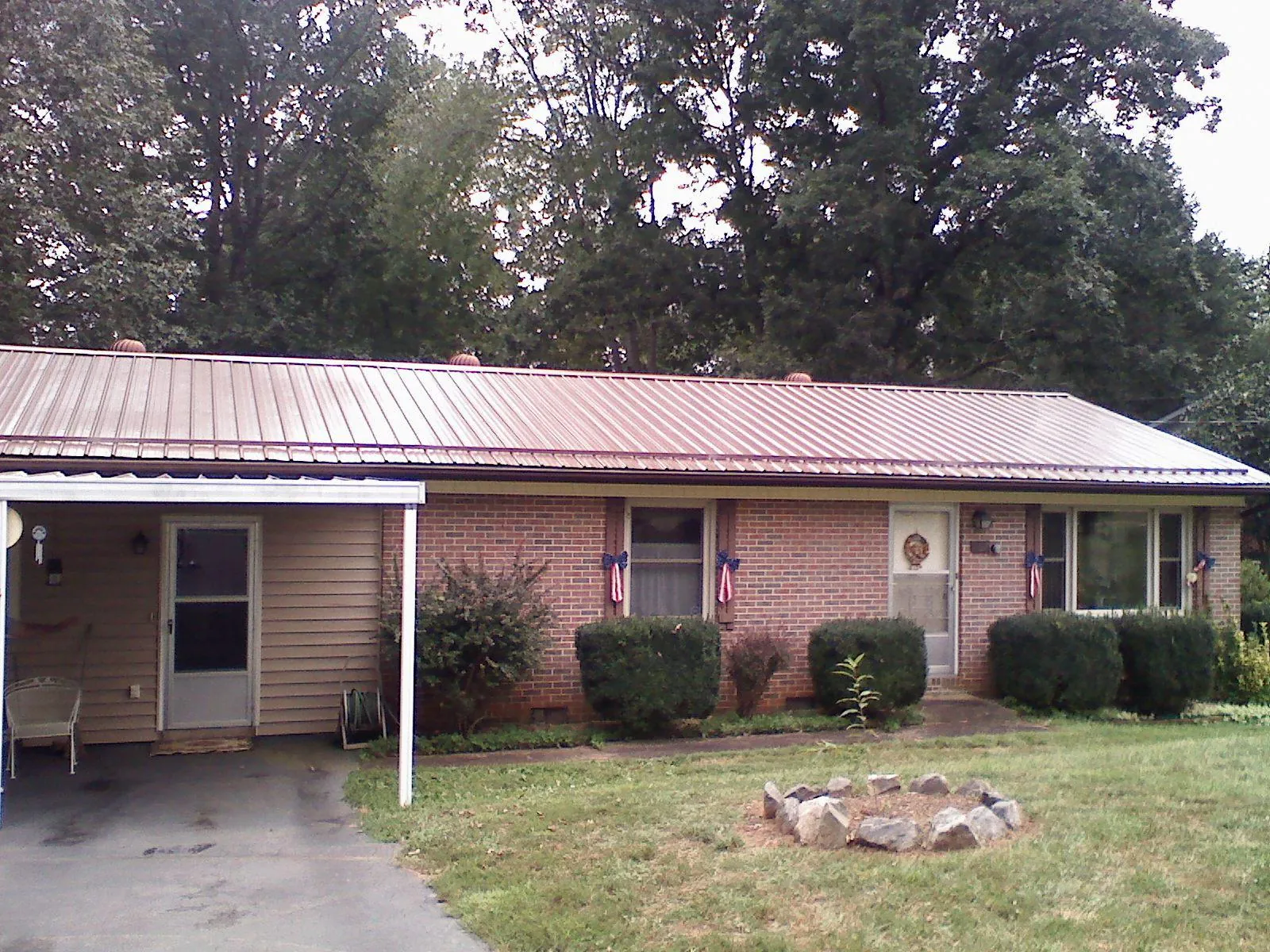Bronze metal roof and carport on a brick ranch home — Roof Repair work by our crew in Stapleton